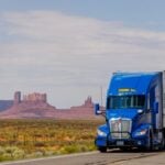 Photo by Igor Passchier: https://www.pexels.com/photo/a-blue-semi-truck-driving-down-a-desert-road-27508769/